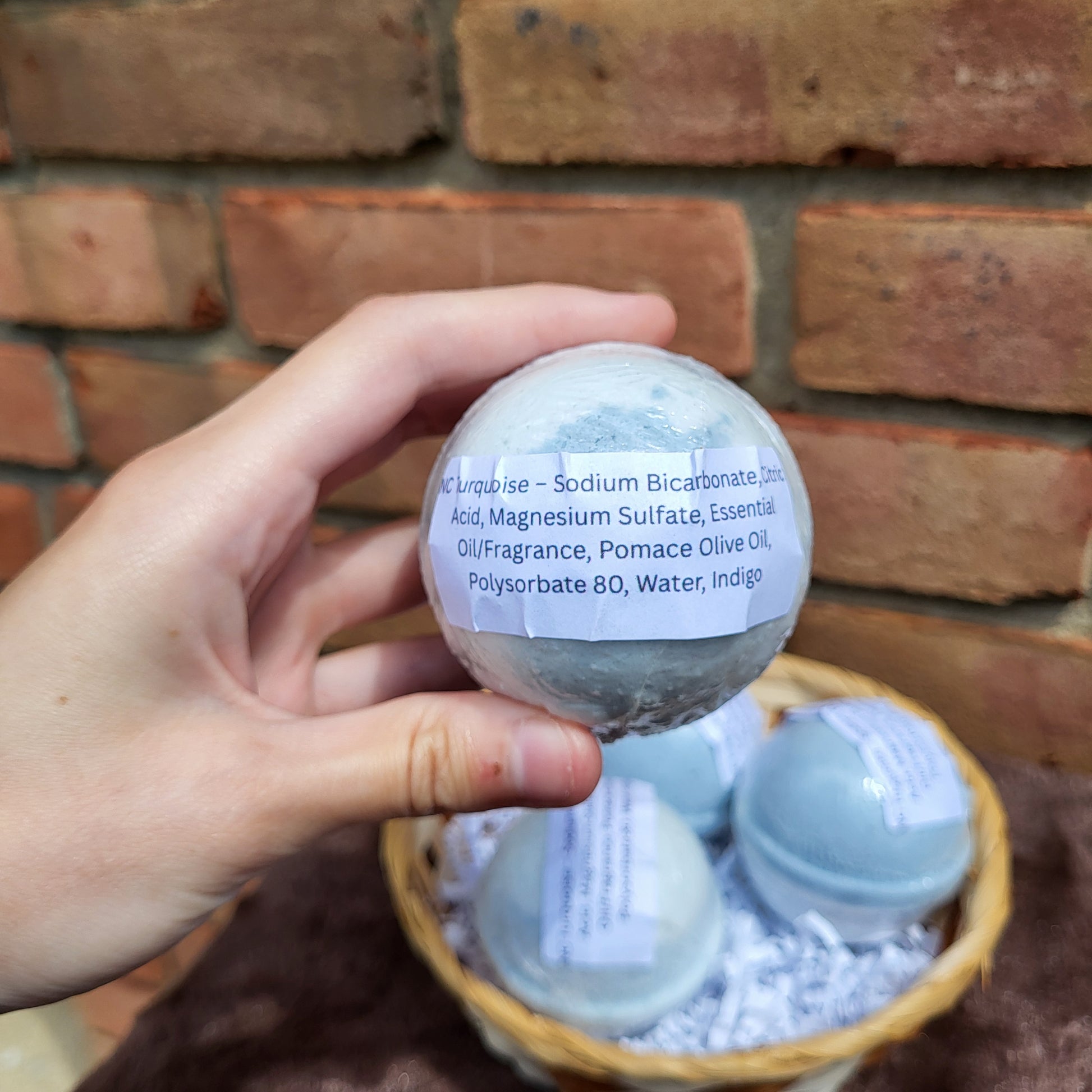 Natural Cedarwood, Lavender & Jasmine bath bomb in hand with a woven basket backdrop
