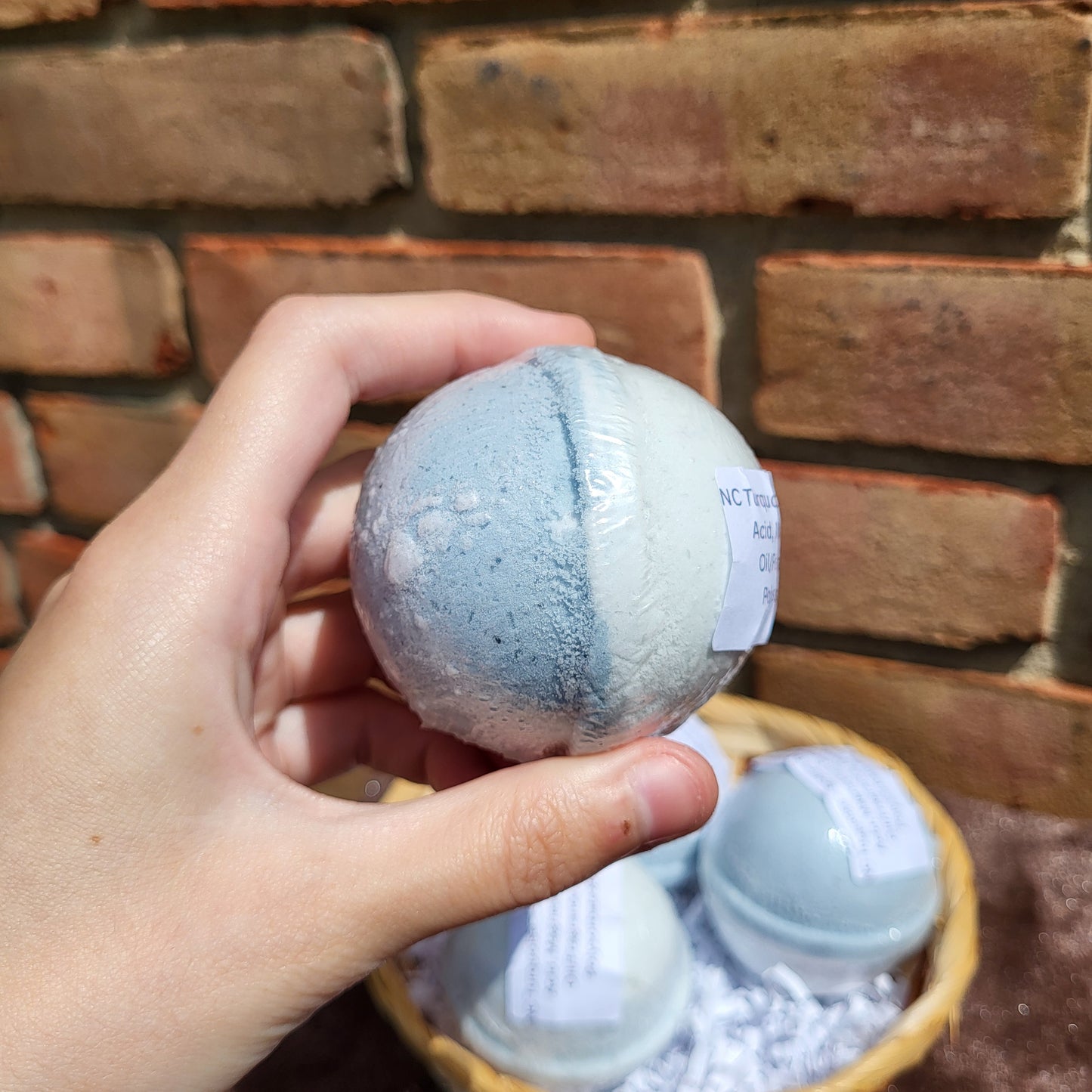 Hand holding a Natural Cedarwood, Lavender & Jasmine bath bomb for relaxing bath experiences