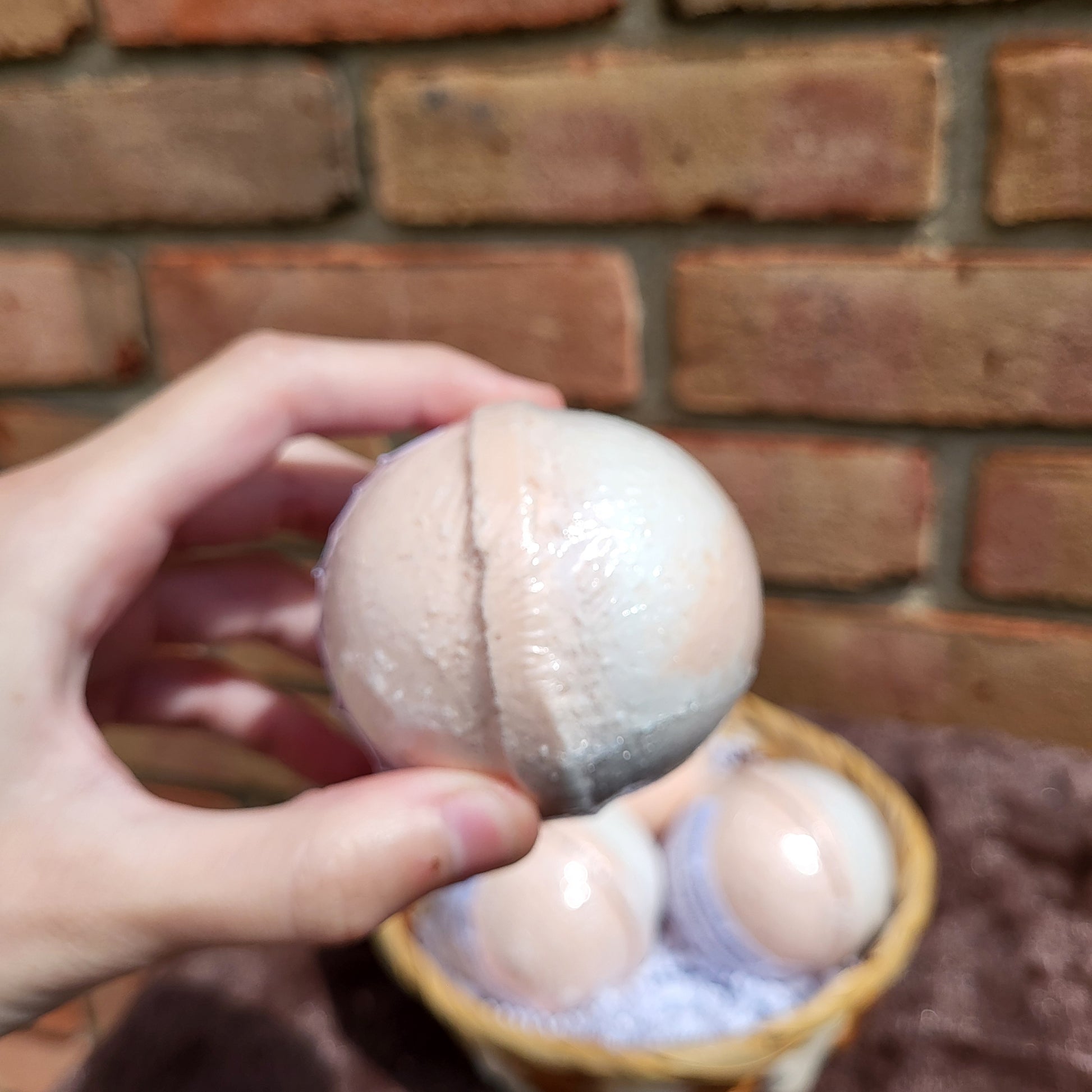 Hand holding Made Natural Bath Bomb with Natural Color Sweet Orange, May Chang & Ginger scent