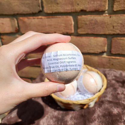 Hand holding a Made Natural bath bomb featuring Natural Color Sweet Orange, May Chang & Ginger ingredients