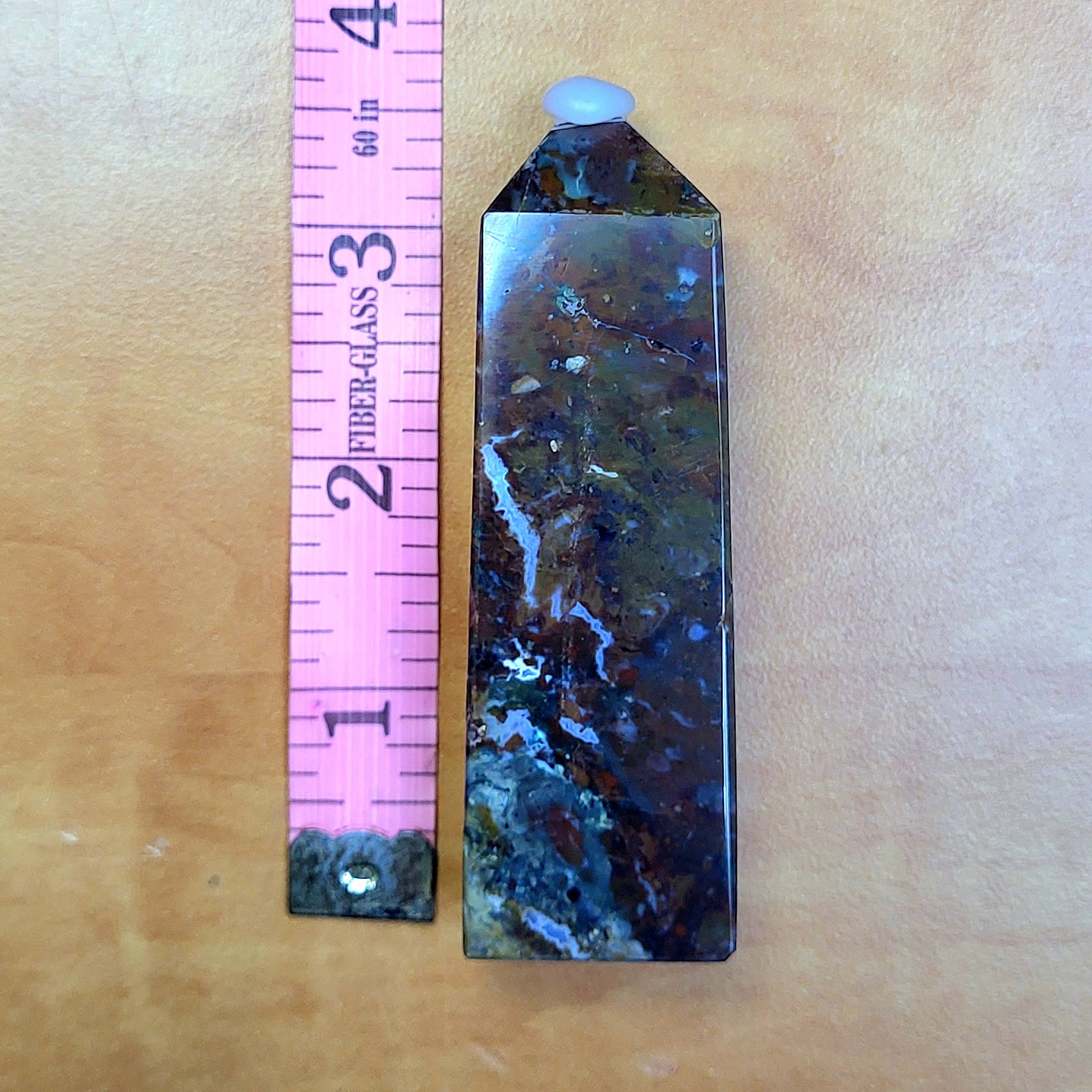 Ocean jasper tower with unique patterns, displayed next to a pink ruler for size comparison