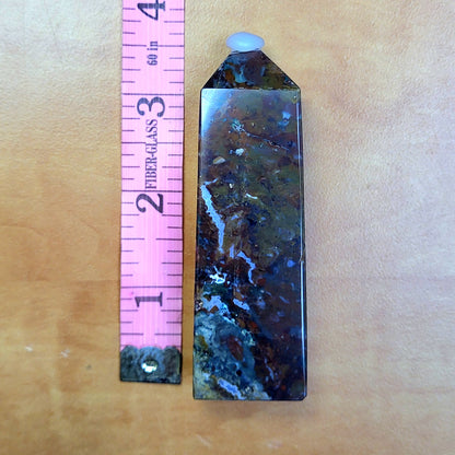 Ocean jasper tower with unique patterns, displayed next to a pink ruler for size comparison