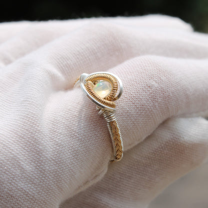 Opal Sterling ring with a unique wire design, elegantly showcased on a soft fabric background