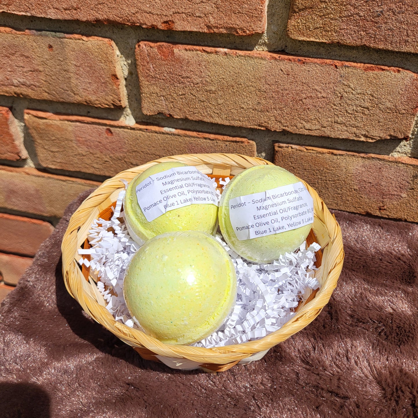 Three Peridot Bath Bombs in a wicker basket filled with decorative shreds for a relaxing soak