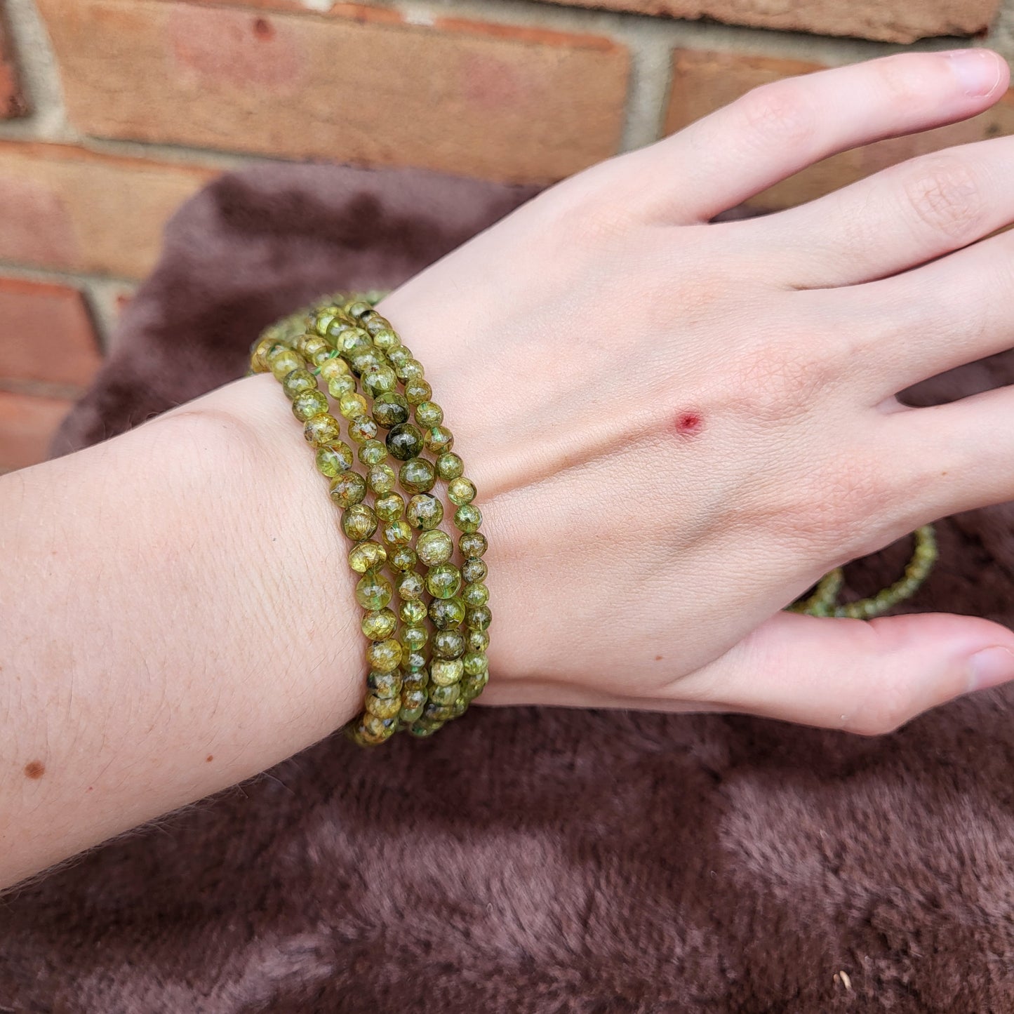 Peridot bracelet displayed on a hand showcasing its vibrant green color and natural stone texture