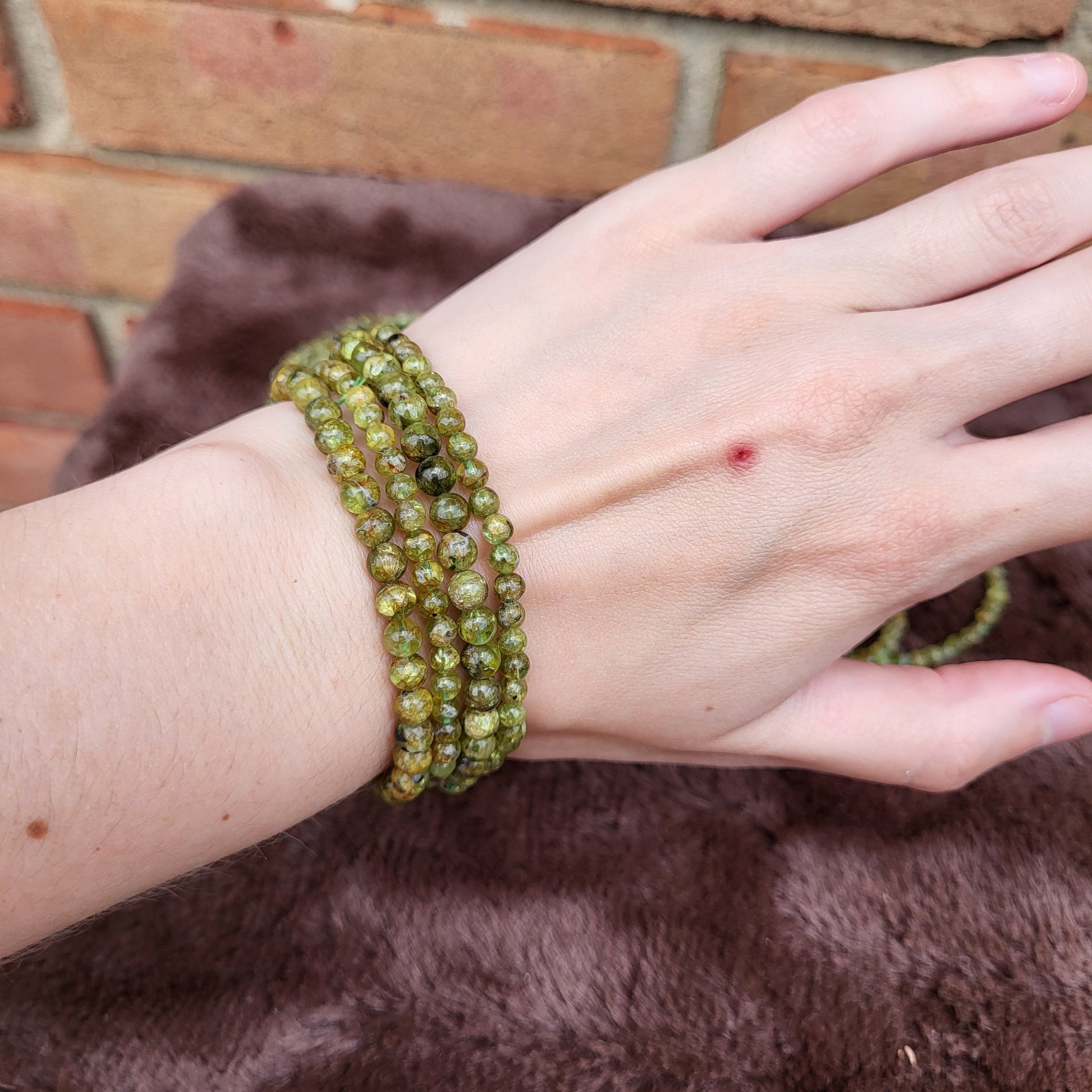 Peridot bracelet displayed on a hand showcasing its vibrant green color and natural stone texture