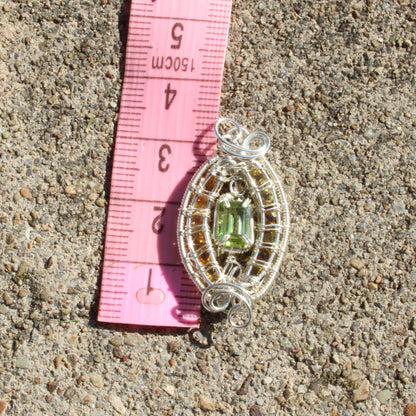Peridot Sterling Silver yellow tourmaline pendant with intricate wire design on a measuring tape