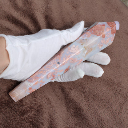 Pink Agate Wand crystal with soft pink and white patterns held by a gloved hand on brown fabric