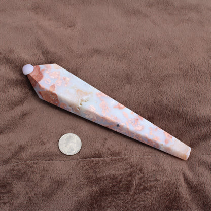 Pink Agate Wand with white and peach tones placed next to a quarter for size reference on brown fabric