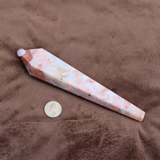 Pink Agate Wand with white and peach tones placed next to a quarter for size reference on brown fabric