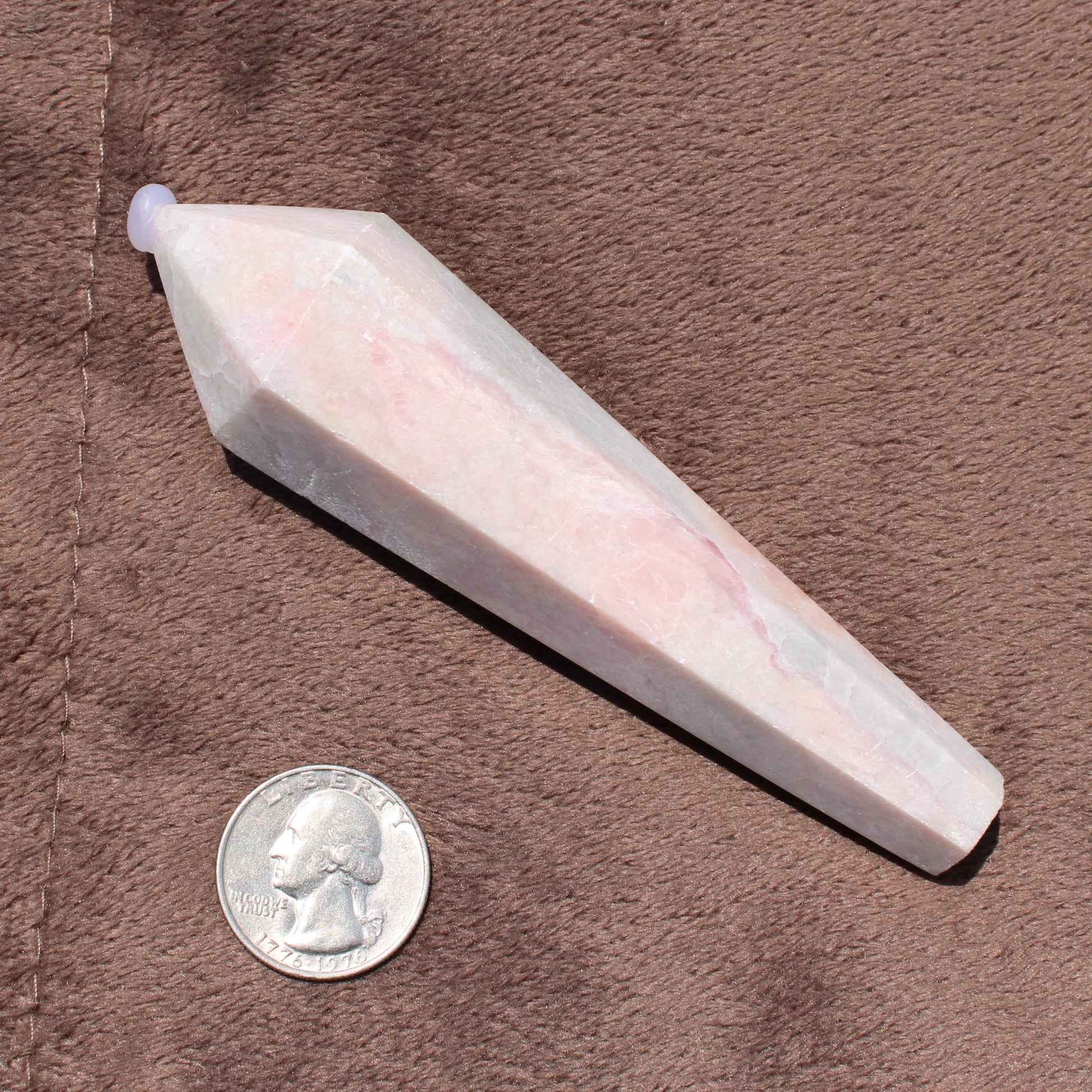 Pink Opal Wand crystal with polished facets shown next to a quarter for size reference