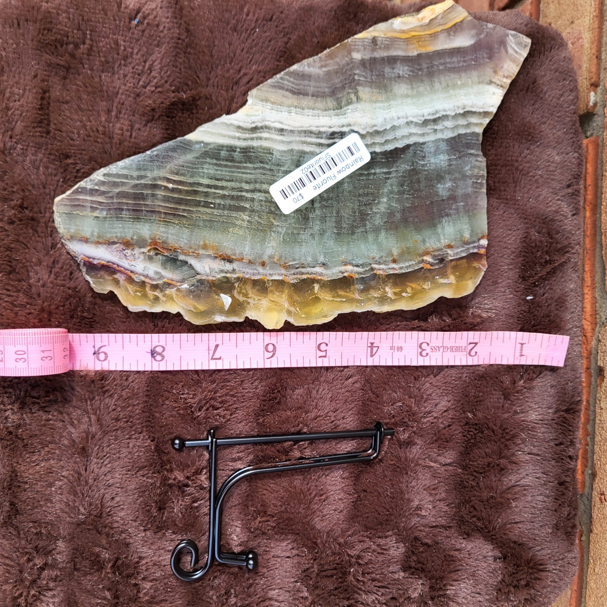 Rainbow Flourite Slab displayed on plush surface with measurement tool for size reference