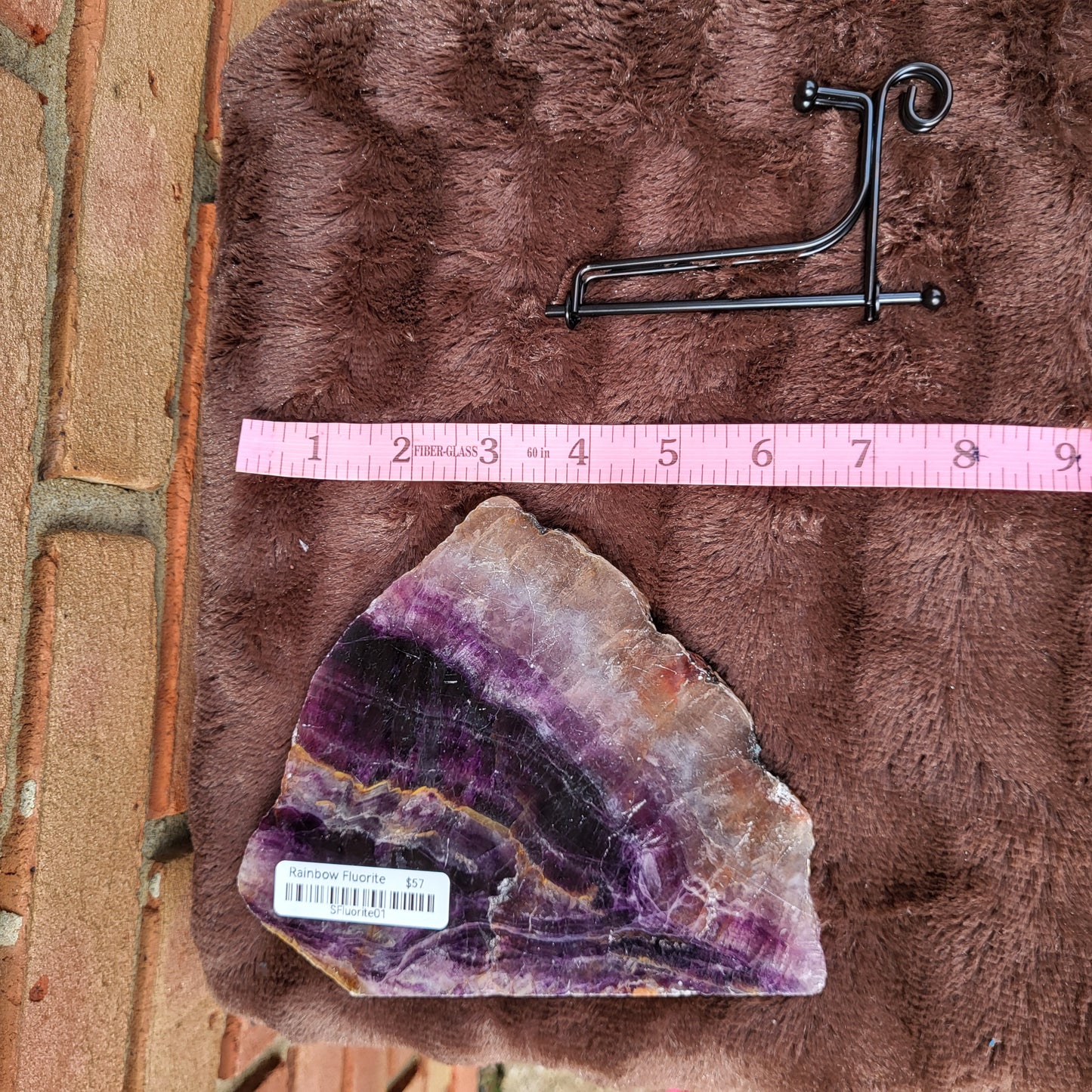 Rainbow Flourite Slab on plush surface with a stand, showcasing vibrant colors and natural beauty