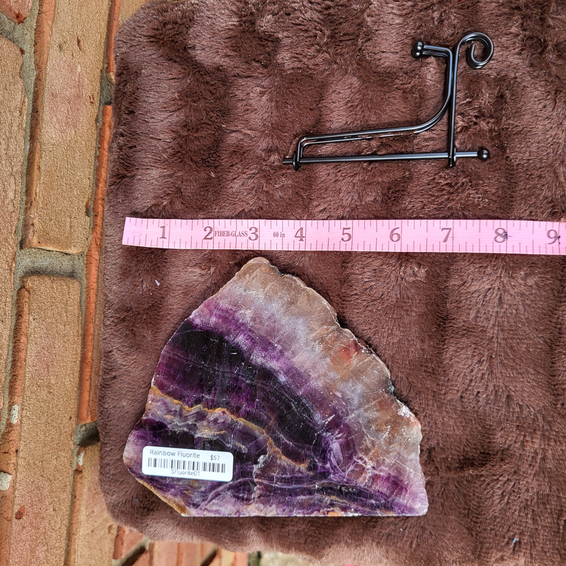 Rainbow Flourite Slab on plush surface with a stand, showcasing vibrant colors and natural beauty