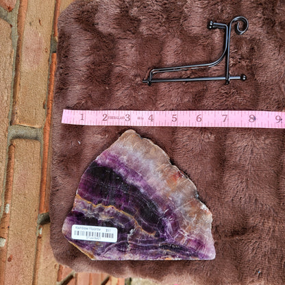 Rainbow Flourite Slab on plush surface with a stand, showcasing vibrant colors and natural beauty