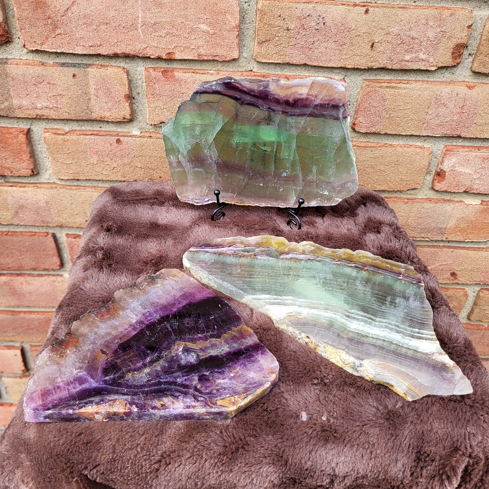 Three Rainbow Fluorite Slabs with Purple and Green Striations Displayed on a Stand