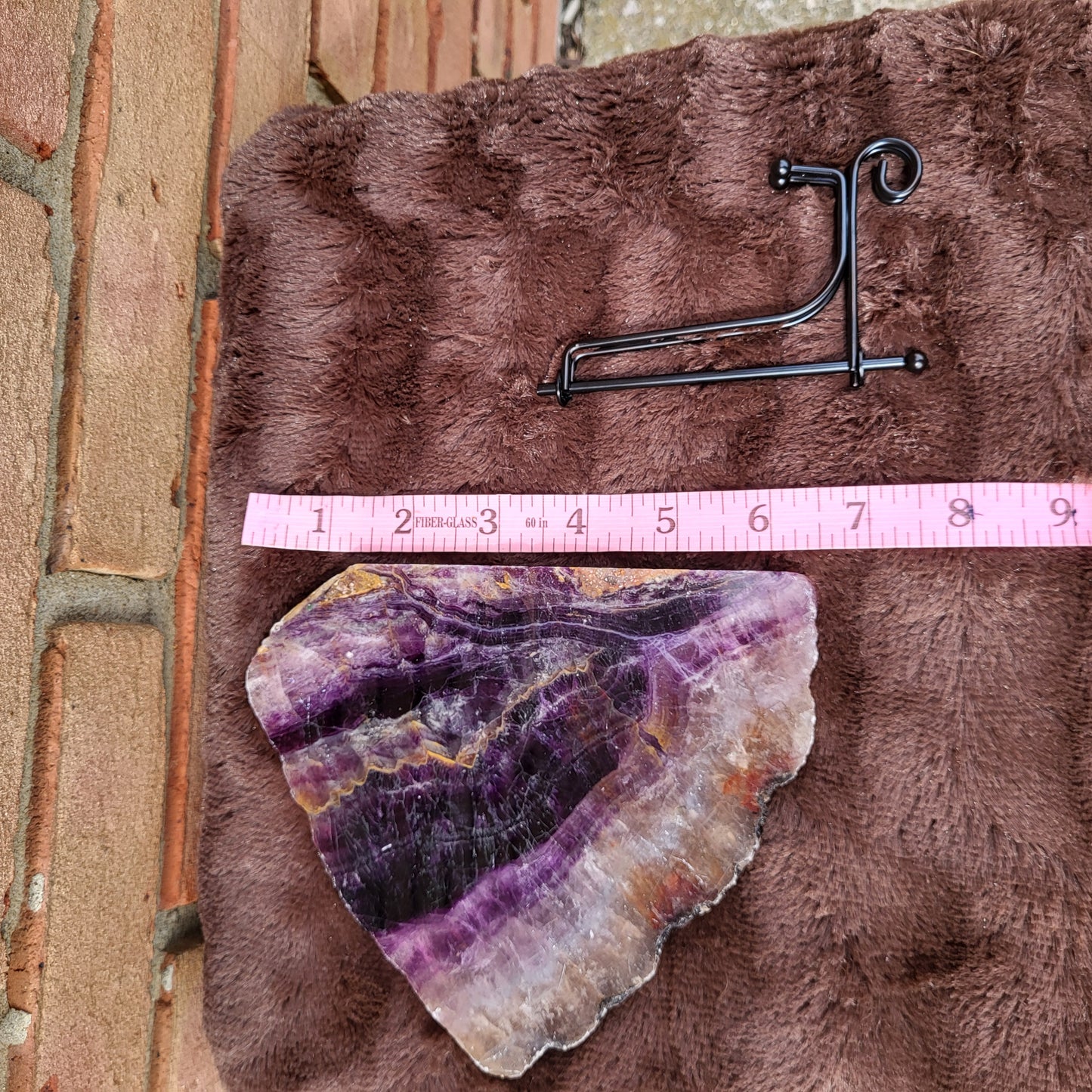 Rainbow Flourite Slab displayed on a soft surface with a metal holder for decorative purposes