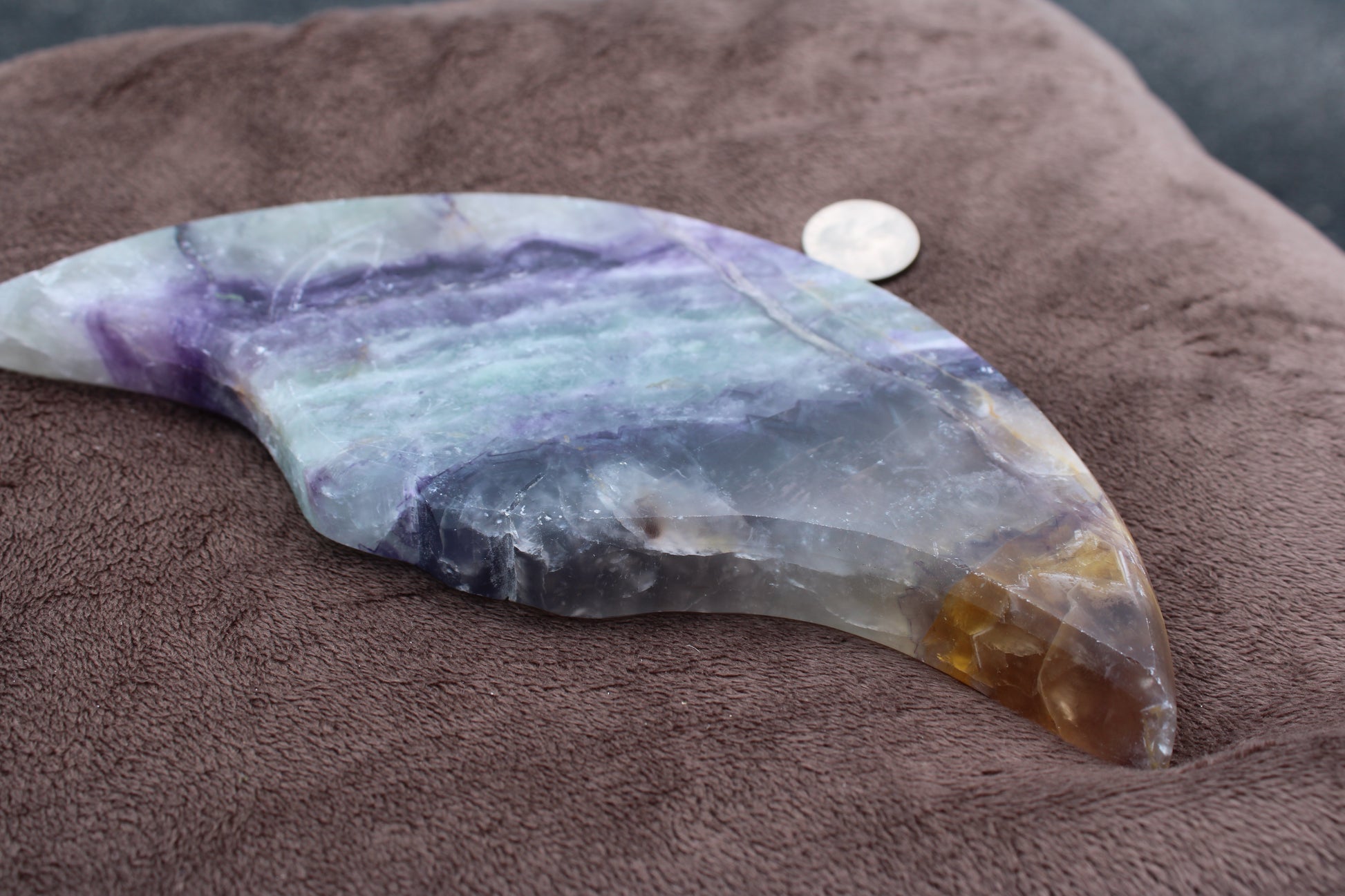 Rainbow Fluorite Cresent Moon Statement Crystal with purple and green hues placed on brown fabric