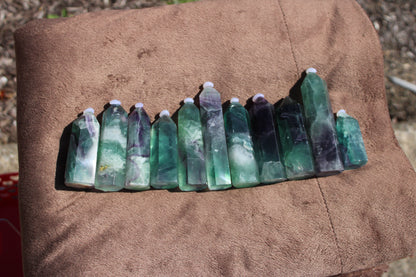Collection of Rainbow Fluorite tower crystals in various shades of green and purple, arranged neatly