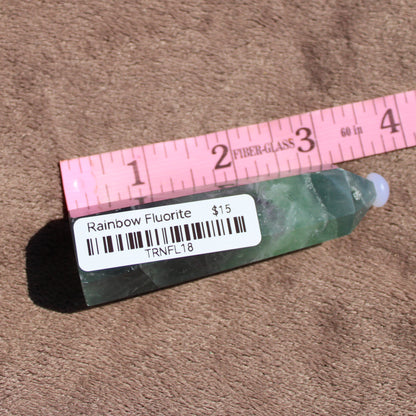 Rainbow Fluorite tower displayed with a ruler, showcasing its vibrant colors and unique shape