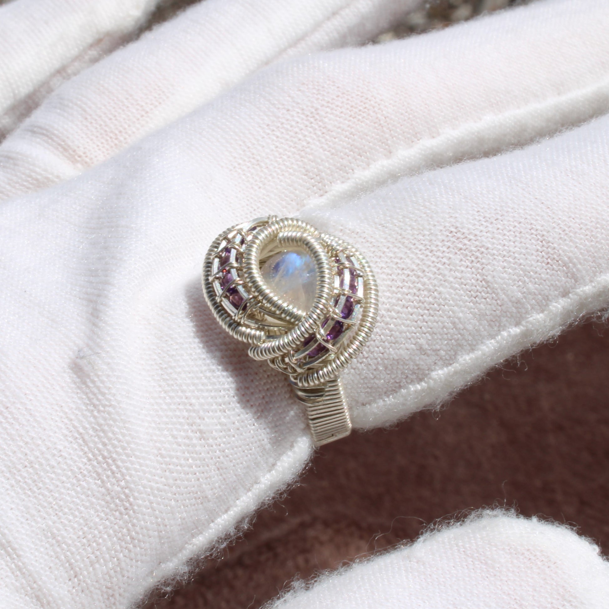 Unique rainbow moonstone and amethyst sterling silver ring displayed on a soft background