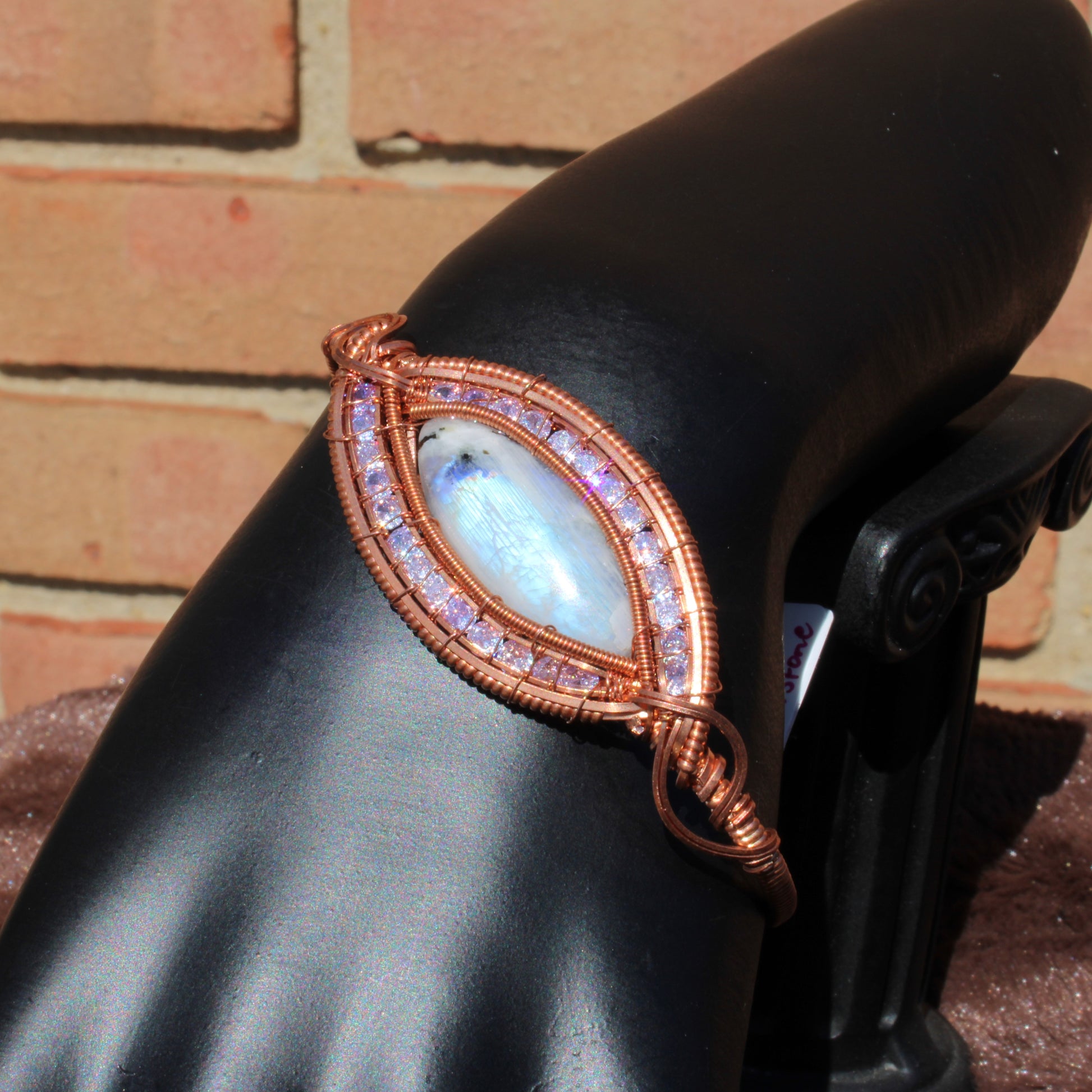 Elegant rainbow moonstone cz bracelet with a unique design showcased on a stand