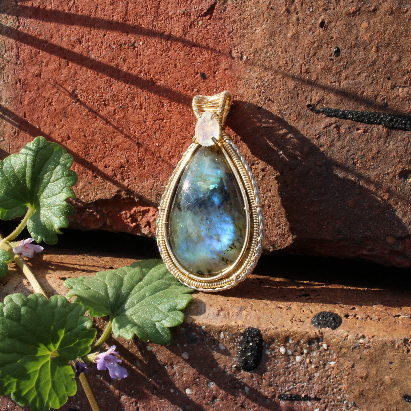 Rainbow Moonstone & Labradorite 14k Gold fill pendant on rustic stone background with greenery