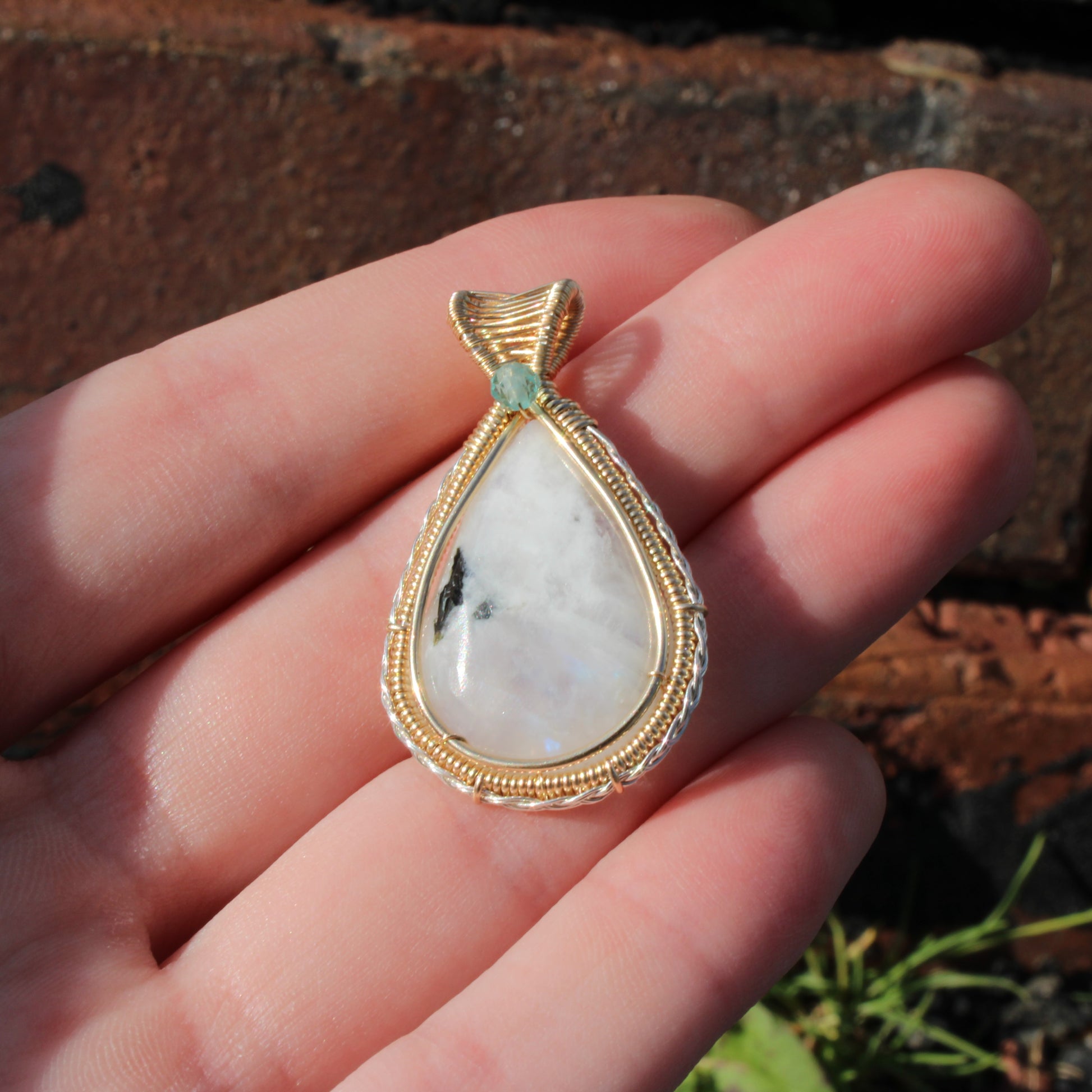 Rainbow moonstone Sterling Silver, 14k Gold Fill pendant with intricate wire design held in hand