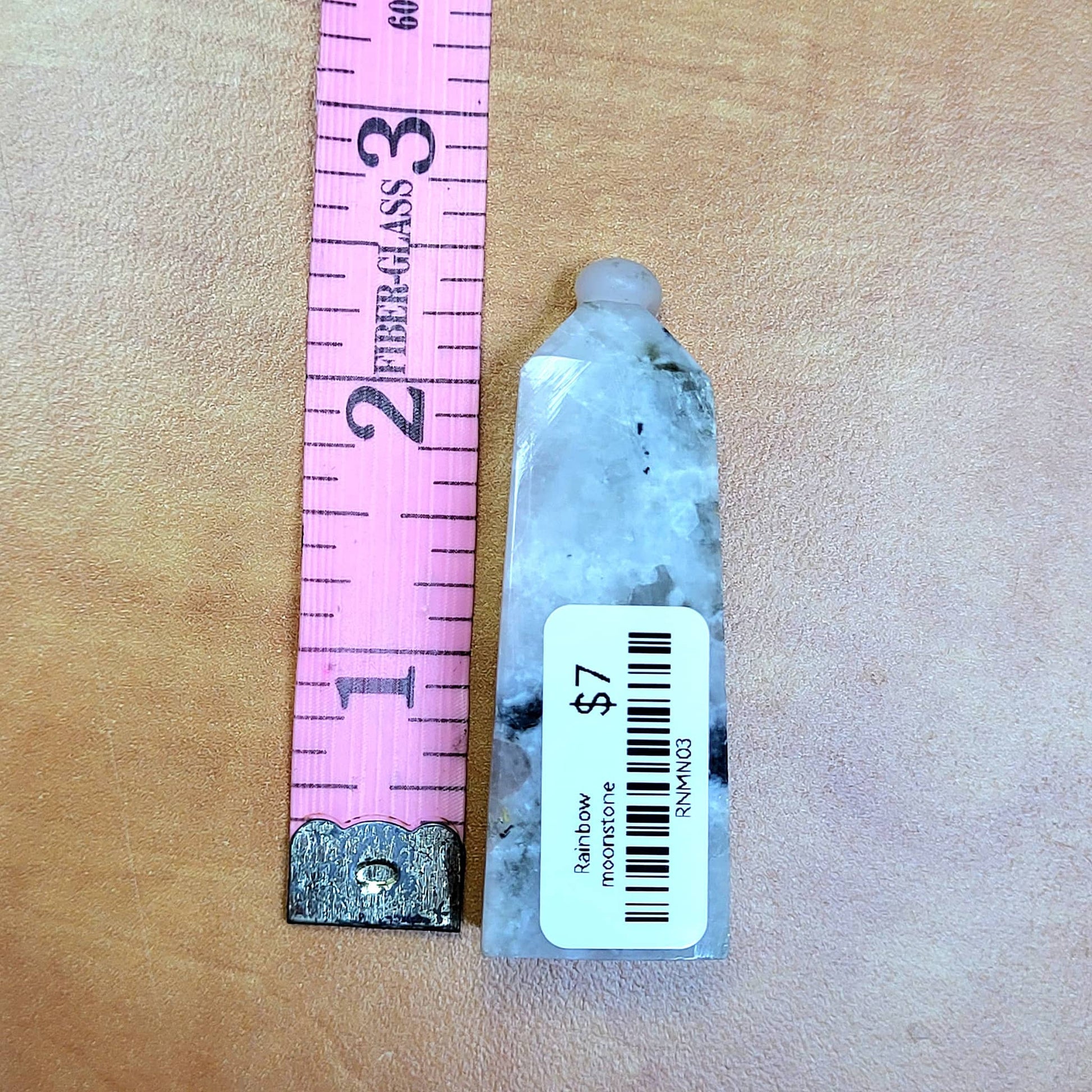 Rainbow moonstone towers showcasing unique gemstone colors and shimmering effects with a measuring scale beside