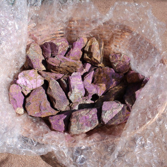 Raw Phosphosiderite stones in a protective bubble wrap, showcasing vibrant purple hues