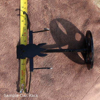 Black metal owl rack next to measuring tape on brown fabric for Red Jasper Owl Wings crystal display