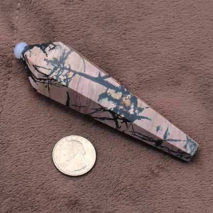 Rhodonite Wand crystal with black veining next to a US quarter for size reference