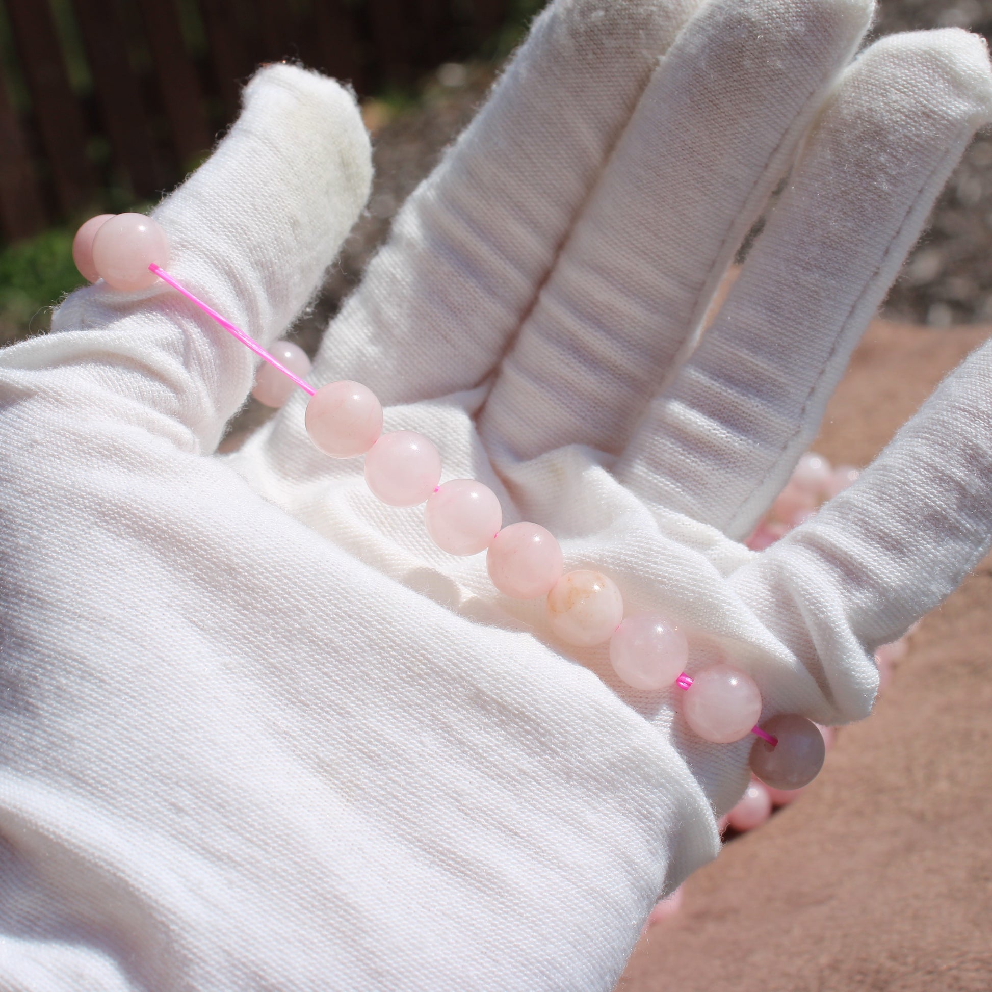 Hand model wearing a Rose Quartz Bracelet made of smooth pink beads, showcasing its beauty and elegance