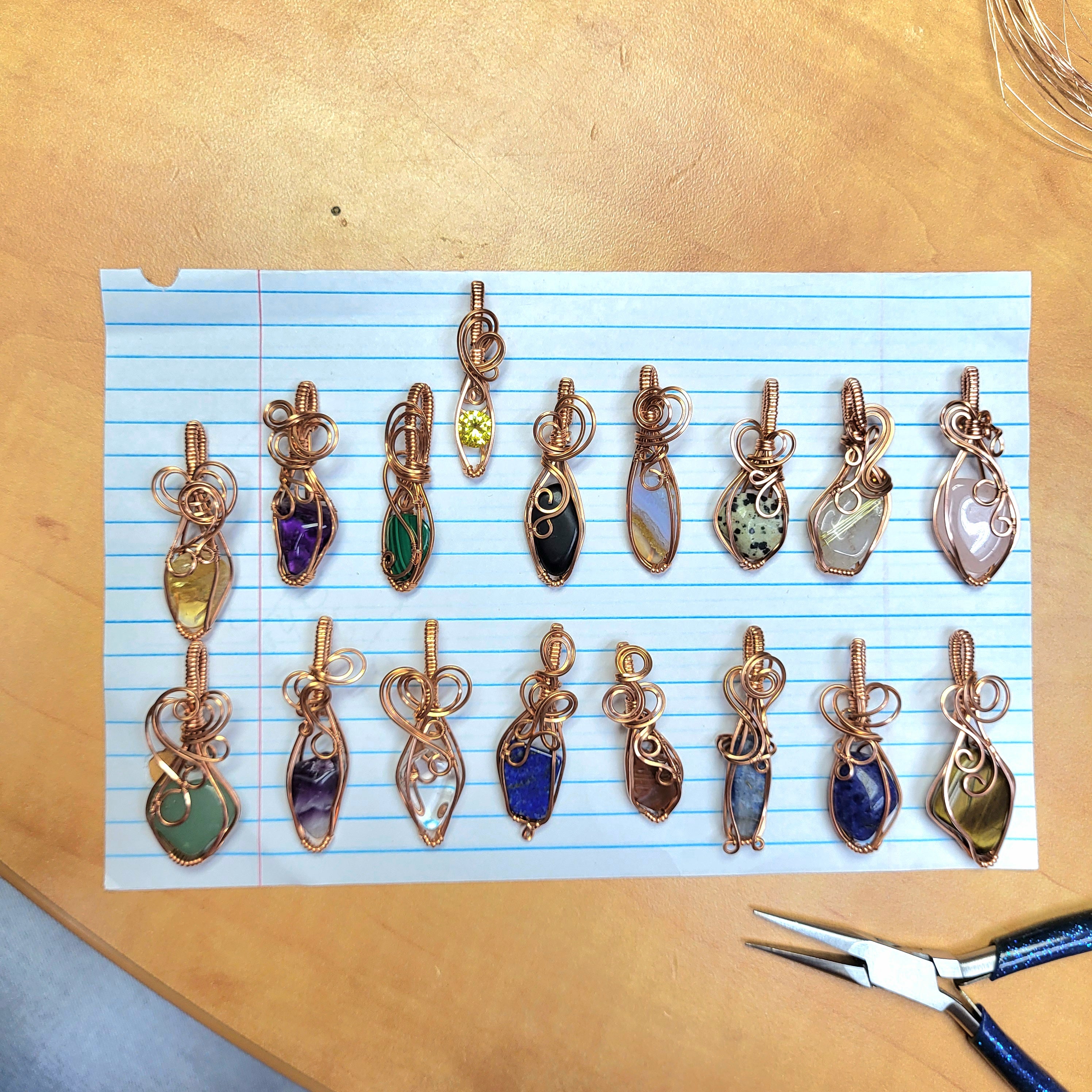 Handcrafted Jewelry Pendants with Various Stones including Rose Quartz on Blue Line Paper