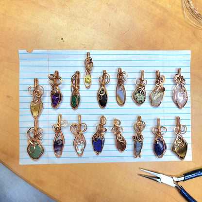 Handcrafted Jewelry Pendants with Various Stones including Rose Quartz on Blue Line Paper