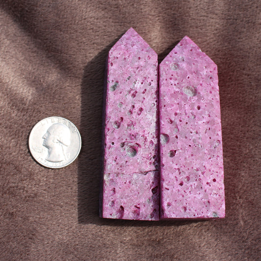 Two Ruby Tower crystals in pink with porous texture next to a US quarter for size comparison