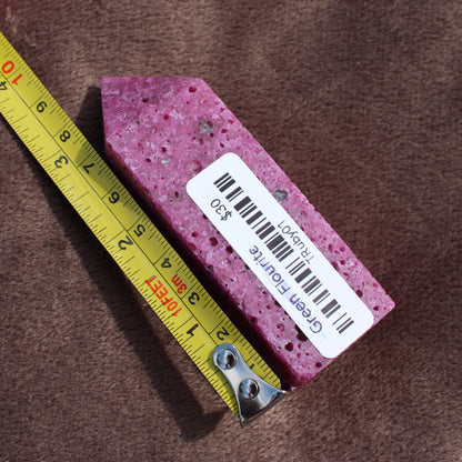 Different Branches LLC Ruby Tower crystal in vibrant pink measured next to yellow tape