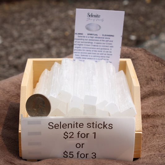 Satin Spar Selenite sticks displayed in a wooden tray with pricing details for cleansing and healing