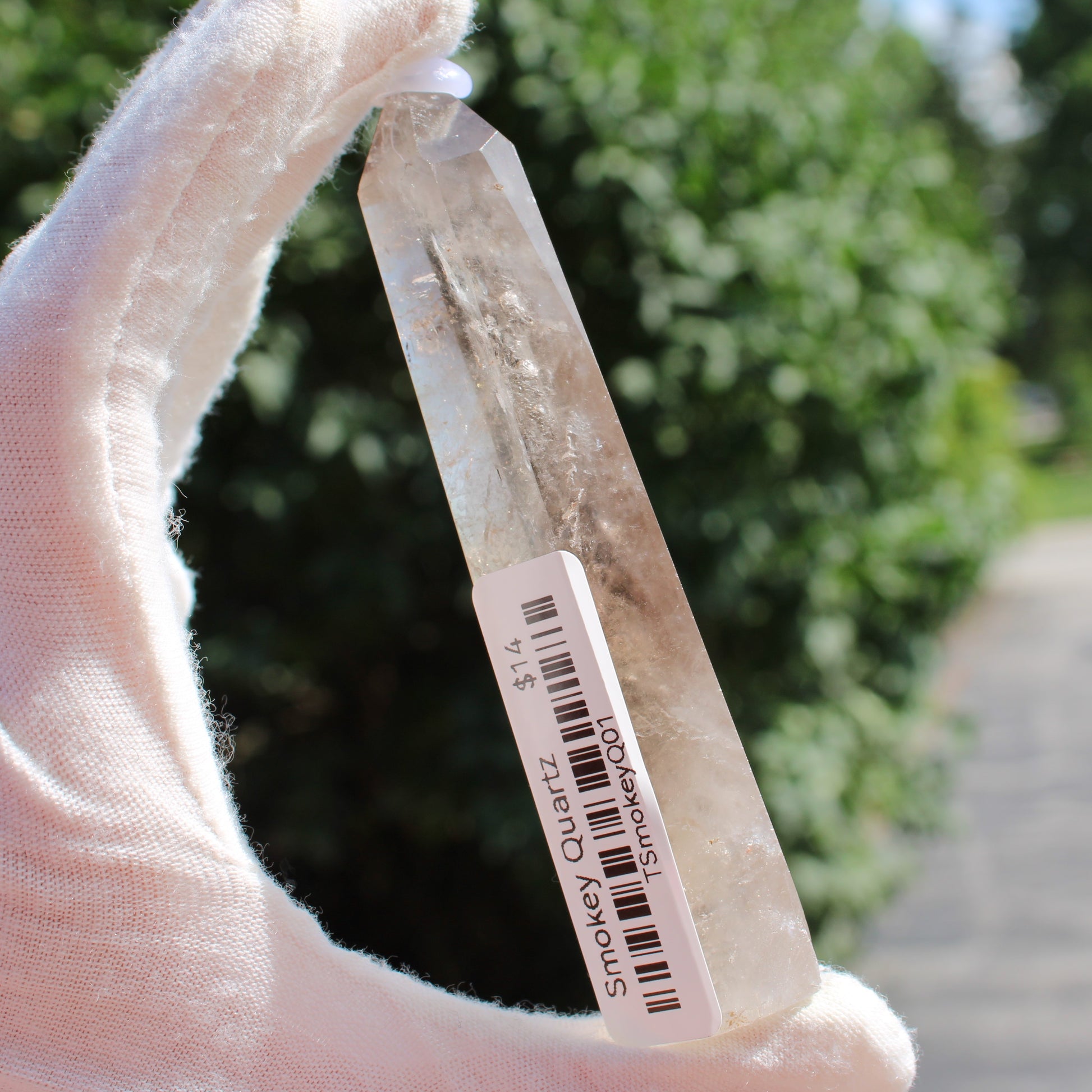 Smokey Quartz Tower crystal held by gloved hand with outdoor background from Different Branches LLC