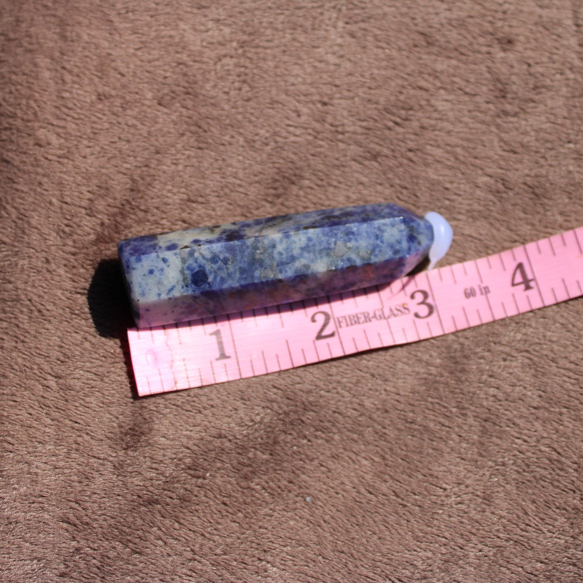 Sodalite tower from Different Branches LLC on beige fabric with a measuring tape for size reference