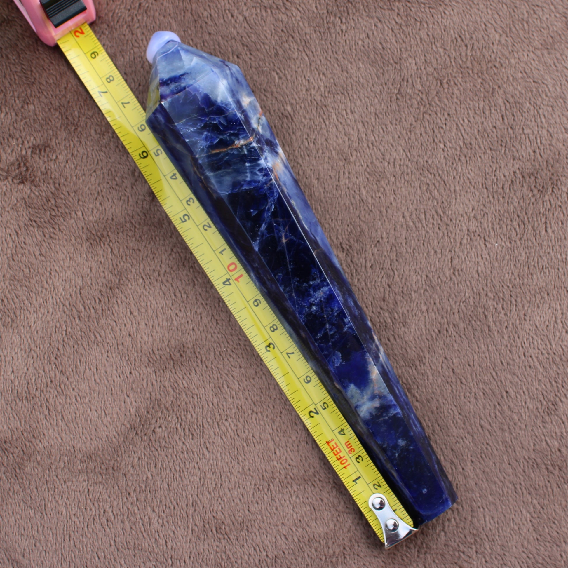 Sodalite Wand crystal from Different Branches LLC placed on brown surface next to a yellow measuring tape