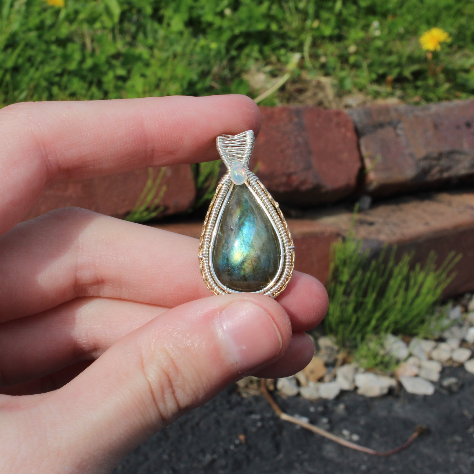 Sterling Silver Labradorite Ethiopian Opal Tear Drop Pendant held in hand, showcasing natural beauty and craftsmanship