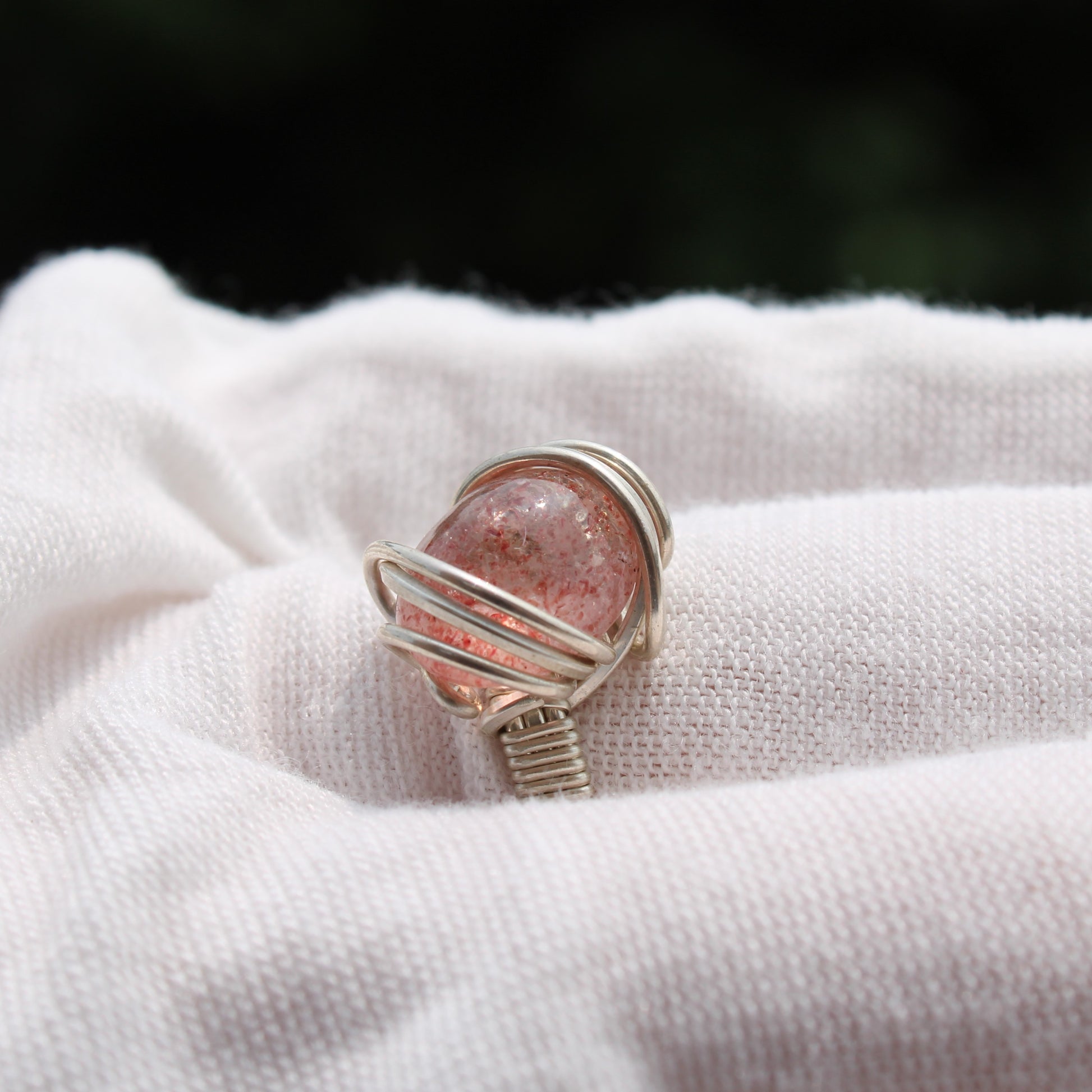 Strawberry quartz ring wrapped in silver wire, showcasing its unique color and design.