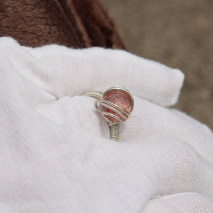 Strawberry quartz ring in silver setting held gently, showcasing its unique color and shine