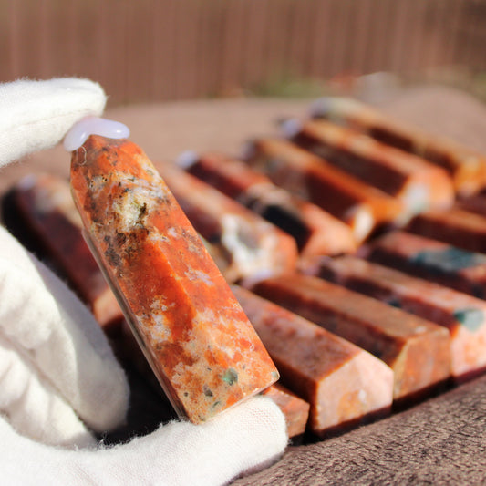 Natural Sunstone tower held in a gloved hand with multiple towers in the background.