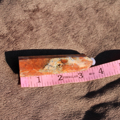 Sunstone tower crystal with vibrant orange hues on textured fabric background
