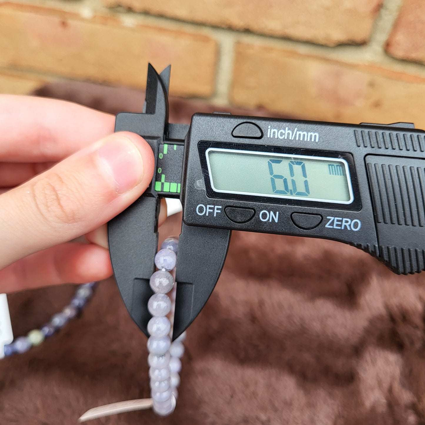 Measuring a Tanzanite bracelet with calipers showing 6mm bead size for clarity and precision