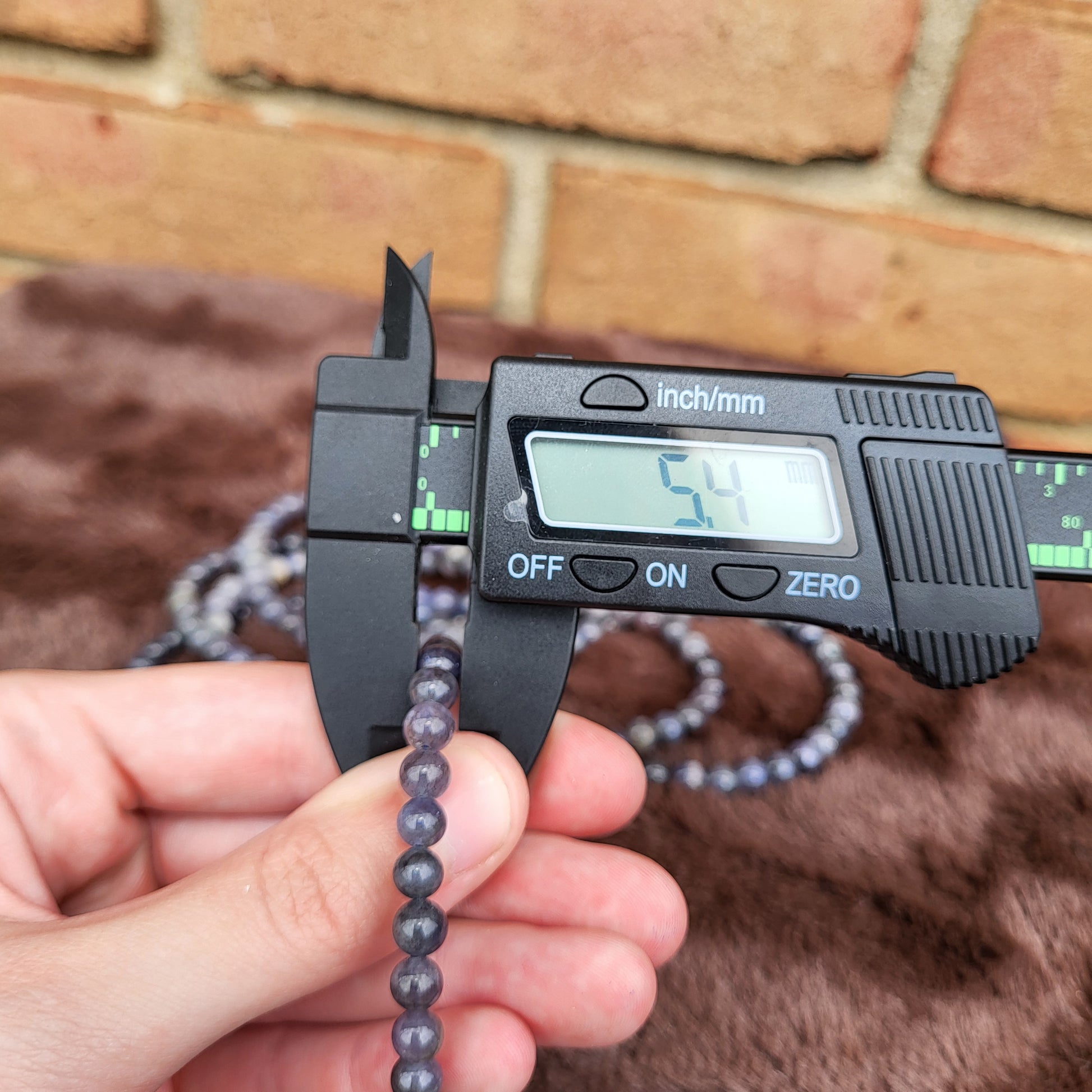 Measuring a Tanzanite bracelet with calipers for size accuracy in a crystal gift shop