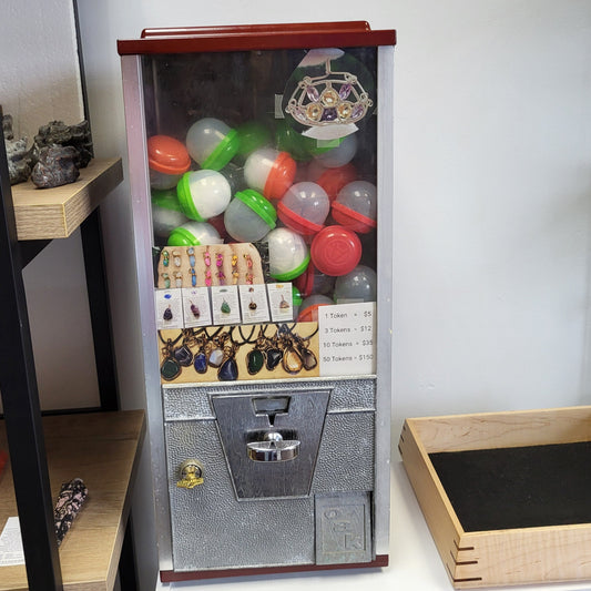 The Token Machine jewelry vending machine by Different Branches LLC filled with colorful capsules and hanging gemstone pendants