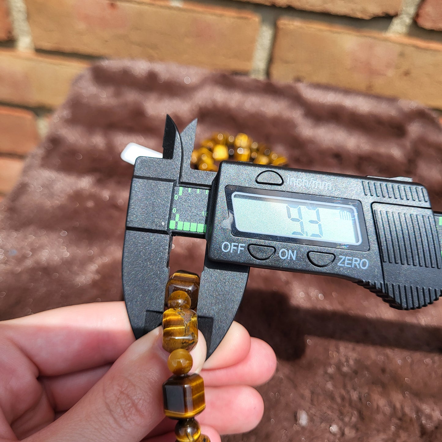 Measuring a tiger eye cube bracelet with a caliper for precision in size and quality